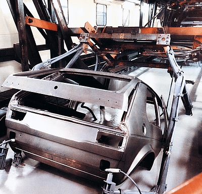 Karosserie eines VW Golf 1 in einer Werkhalle.